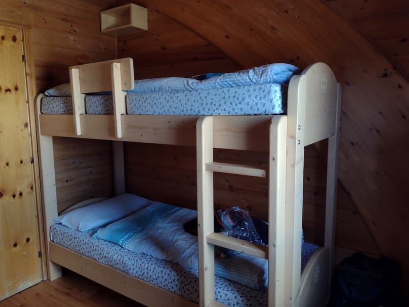 Wooden bunk beds with blue bedding inside a room with angled wood-paneled walls.