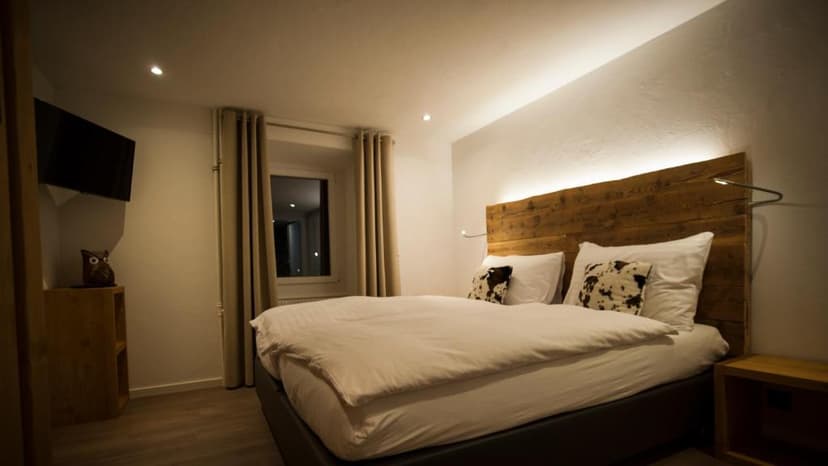 Cozy hotel bedroom with white bedding, rustic wood headboard, and dim lighting