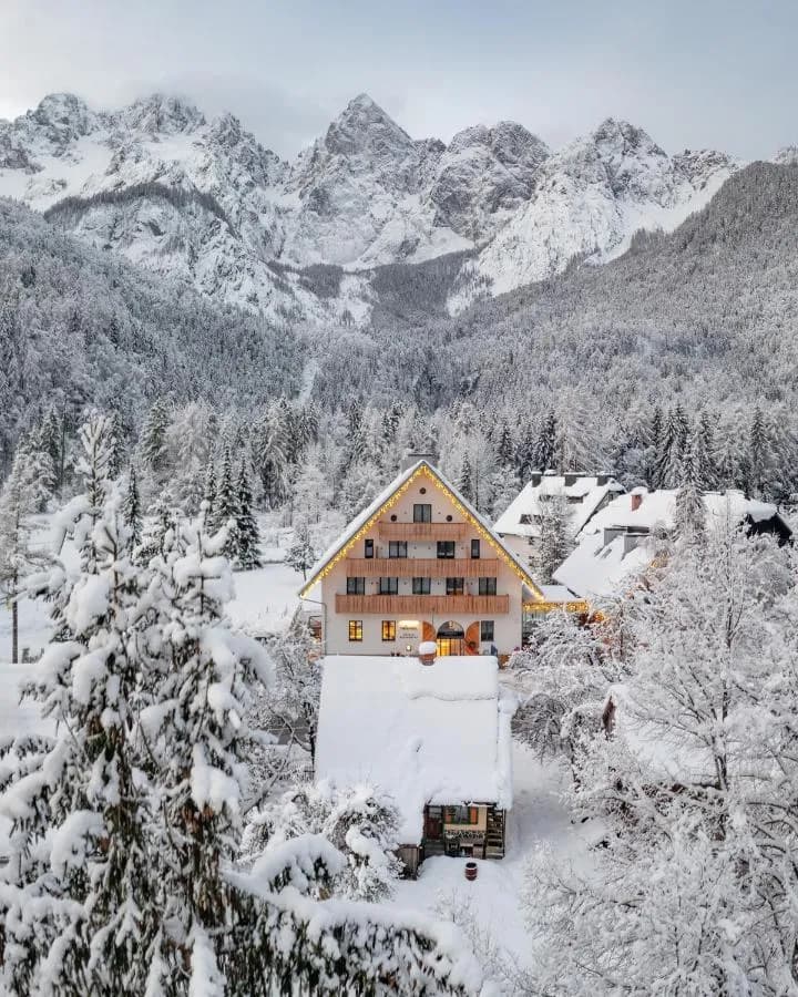 Alpine hotel with wooden balconies surrounded by heavy snow and towering, snow-covered mountains