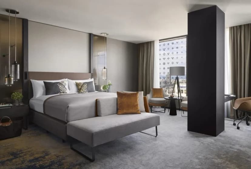 King Deluxe hotel room with modern gray bedding, seating area, and city view.