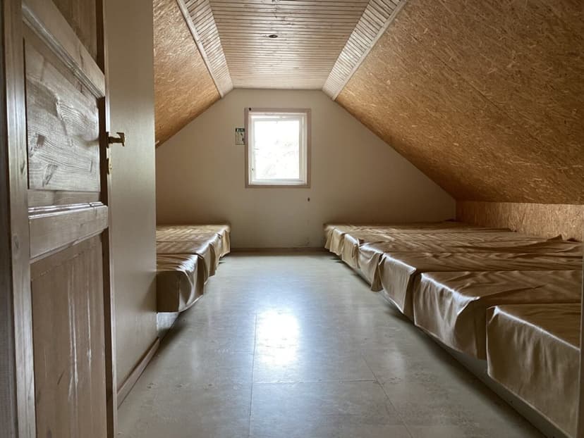 Interior of Álfavatn hut showing simple sleeping platforms with tan covers under sloped OSB walls.