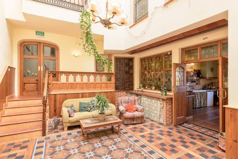 Indoor courtyard seating area with patterned tile floor, wooden staircase, and view into a kitchen.