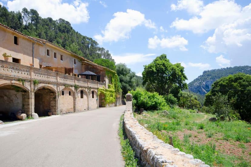 Agroturismo Son Viscos building with arched stone facade next to a road in a green, mountainous setting.