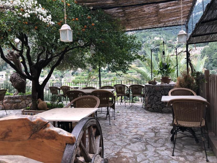 Outdoor dining patio with wicker chairs, stone floor, and mountain view at Hostal Villa Verde.