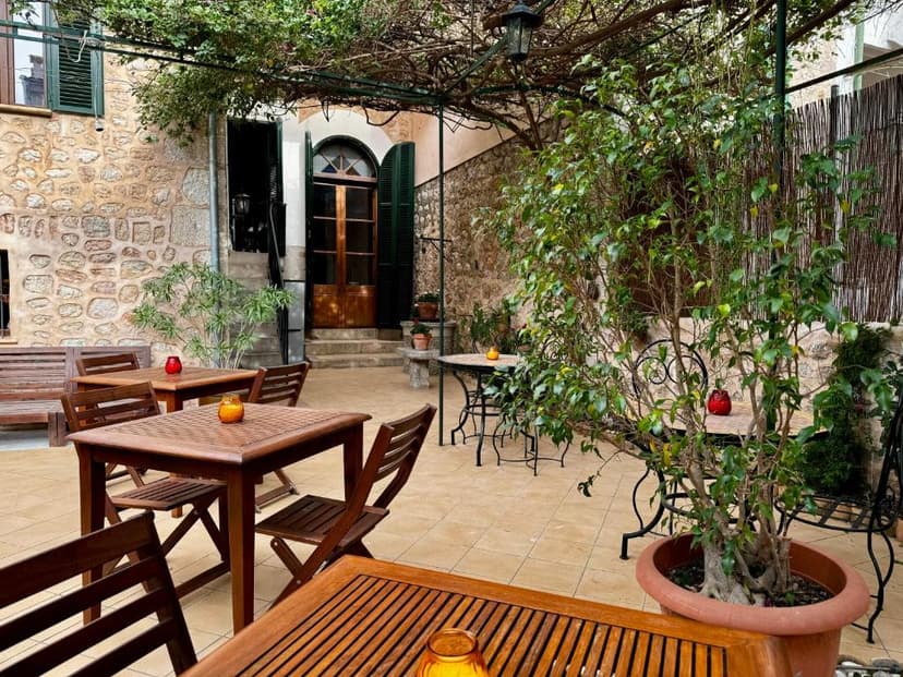 Outdoor dining patio with wooden tables, stone walls, and lush greenery at Hotel Casa Bougainvillea.