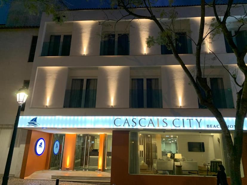 Cascais City & Beach Hotel exterior illuminated at night with a street lamp and tree branches.