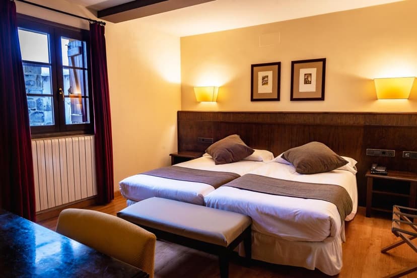 Twin beds in Hotel Valle De Izas room with warm lighting and dark wood accents
