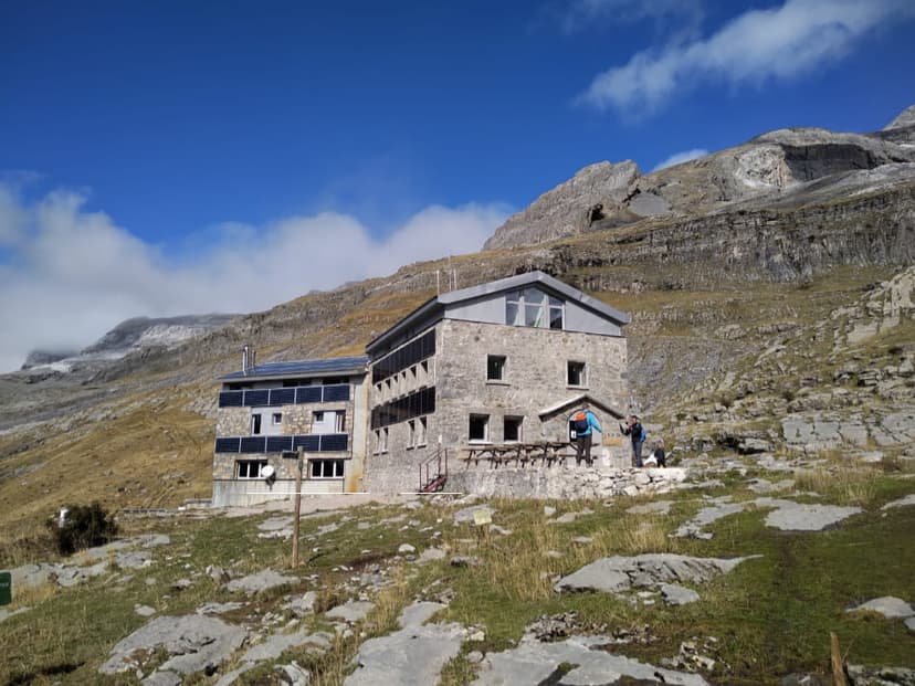 Refugio Góriz stone mountain hut with solar panels below rugged peaks and blue sky