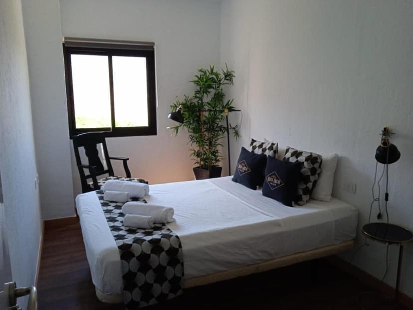 Bedroom with white walls, dark wood floor, and a bed with white linens and patterned runner.