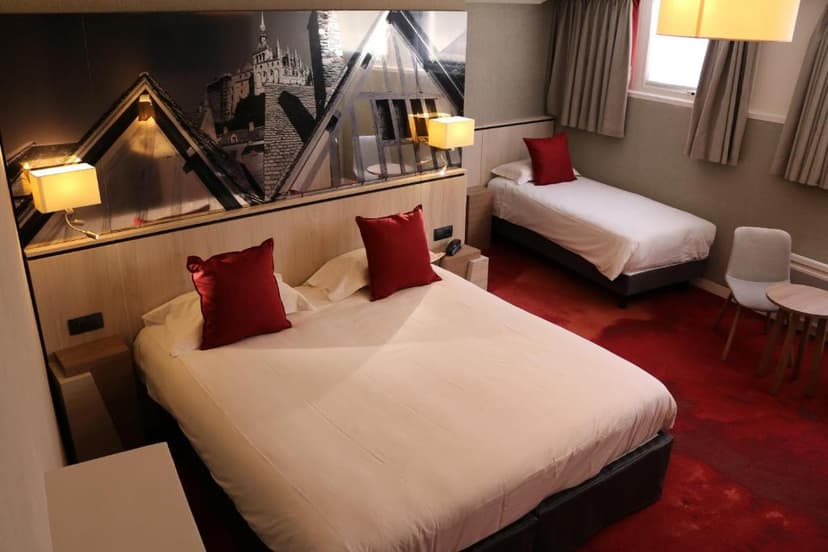 Hotel room with double bed, single bed, red carpet, and black and white cityscape headboard art.