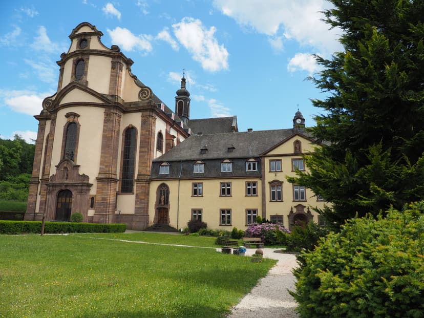 Kloster Himmerod abbey building with Baroque facade, green lawn, and blue sky.