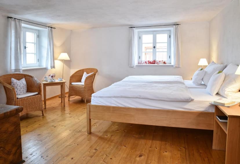 Hotel Garni Gentner twin room with wooden floor, white bedding, and wicker chairs.