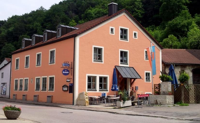 Gasthof zum Brunnen with outdoor seating against a backdrop of green forested hills.