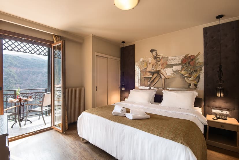 Hotel bedroom with mural art, balcony access, and mountain view in Lagadia.