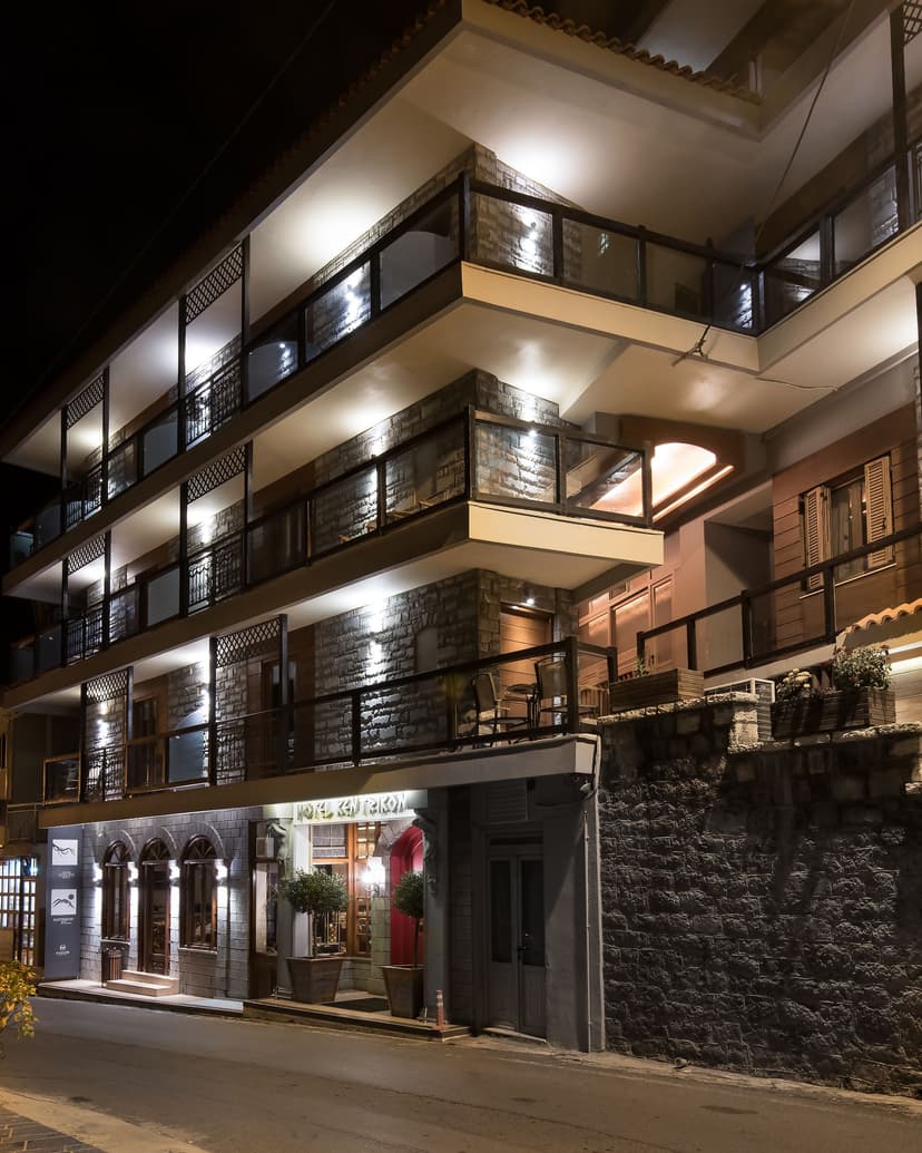 Stone and wood hotel exterior illuminated at night with balconies and street view in Lagadia.