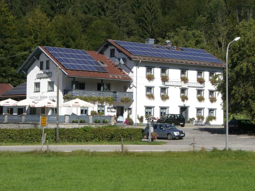 Gasthof Pension Weber building with solar panels, parked cars, and forest background