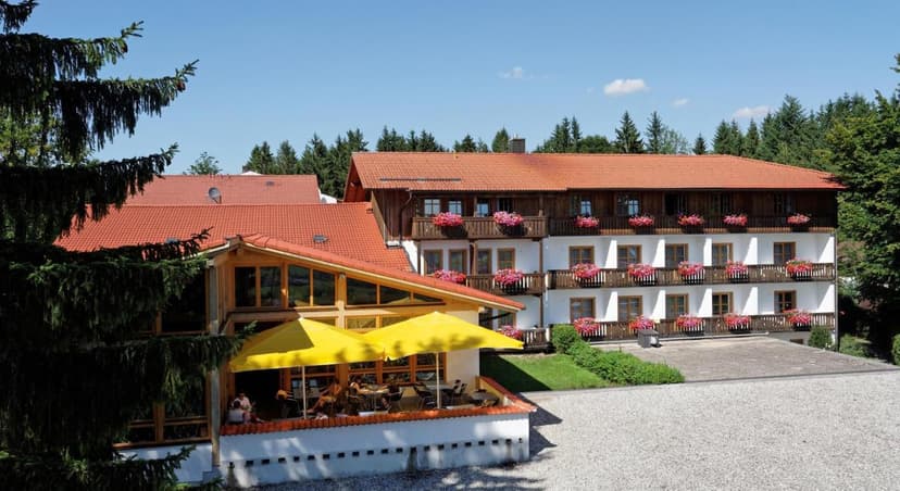 Landhotel Tannenhof with white facade, red roof, and outdoor dining under yellow umbrellas.