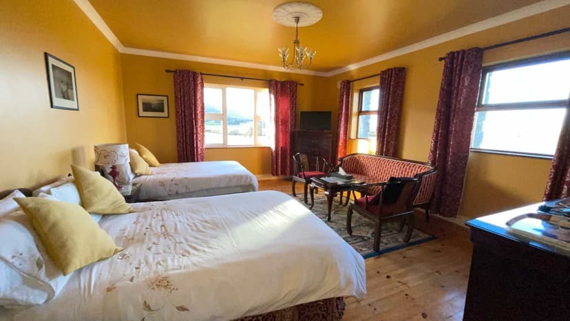 Twin bedroom in Cappabhaile House with yellow walls, white bedding, and view of green hills.