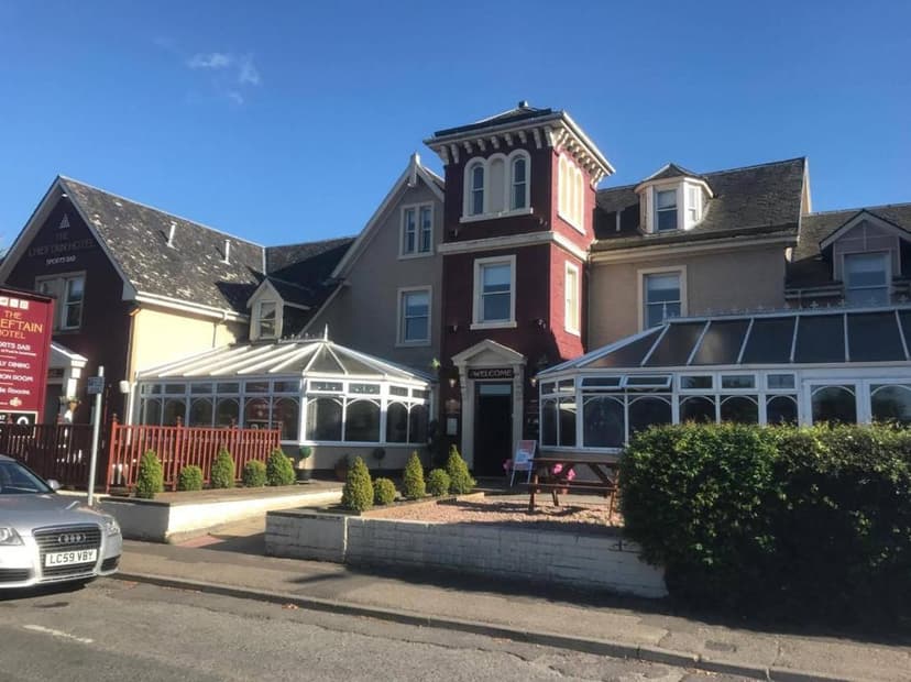 The Chieftain Hotel building with red brick tower and glass conservatories under blue sky.