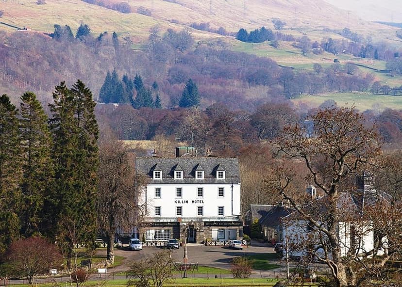 Killin Hotel building nestled in valley with rolling hills and bare trees in background