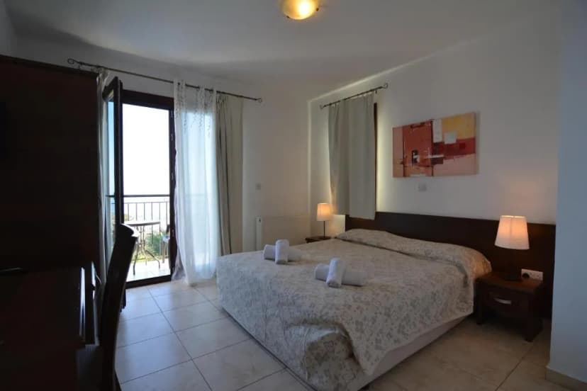 Bedroom in Palatos Hotel with double bed, balcony access, and tiled floor
