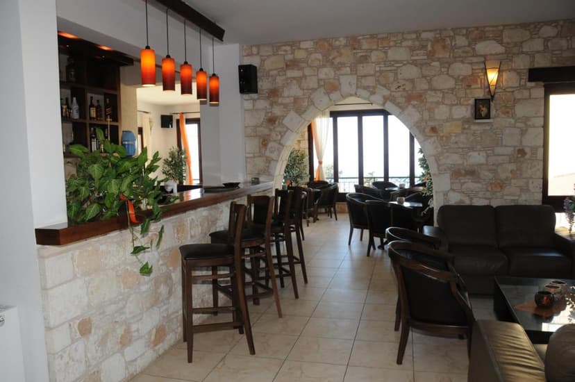 Lobby bar area with stone walls, wooden bar, and dark leather seating overlooking bright windows.