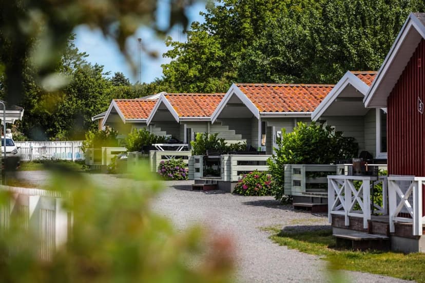 Row of light green vacation cabins with orange tile roofs and lush greenery in foreground.