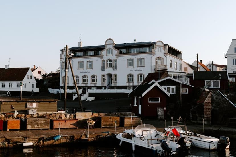 Boats docked in harbor before Hotel Sandvig Havn buildings in coastal town.