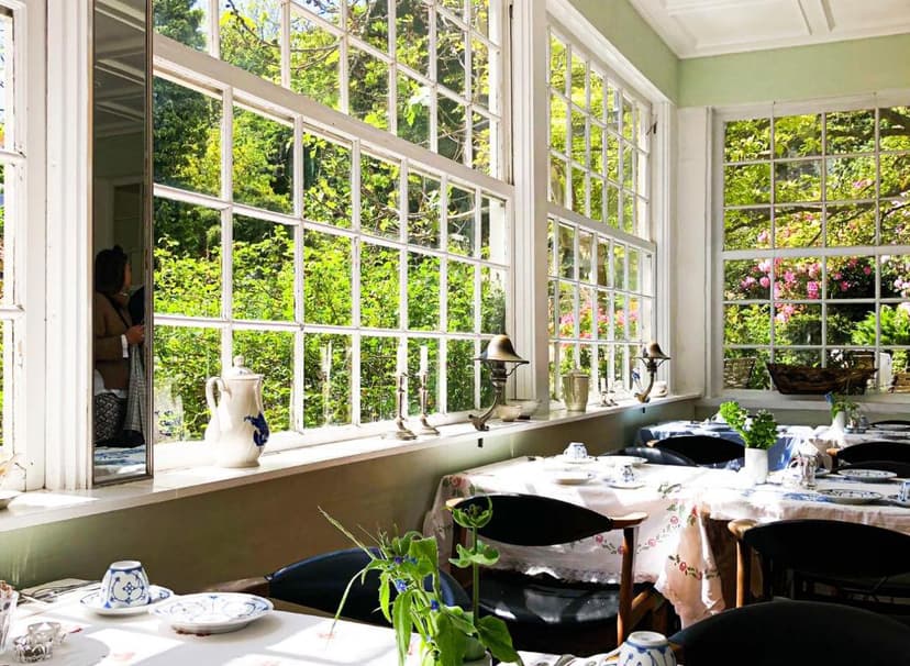 Dining room with large paneled windows overlooking lush green garden foliage and flowers