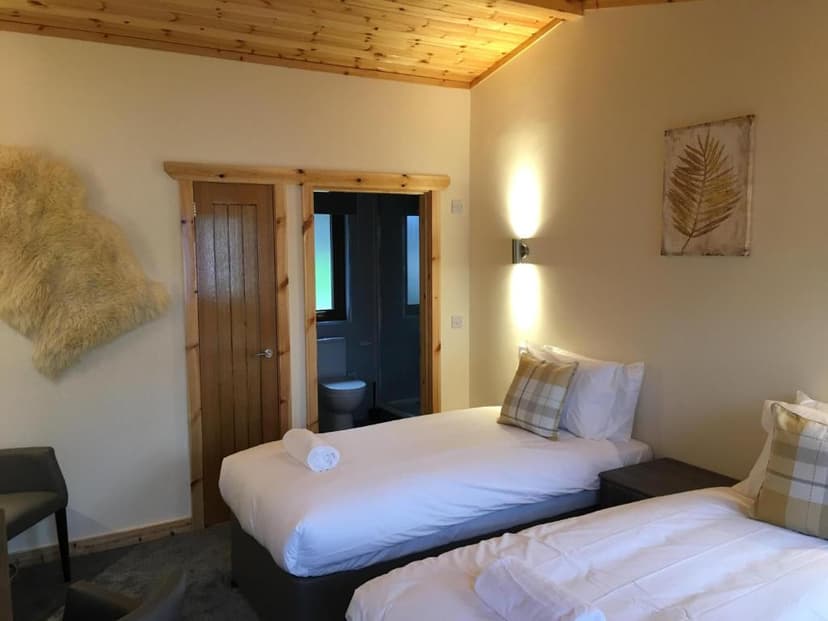 Twin bedroom with wood ceiling, ensuite bathroom visible, and sheepskin rug on wall.