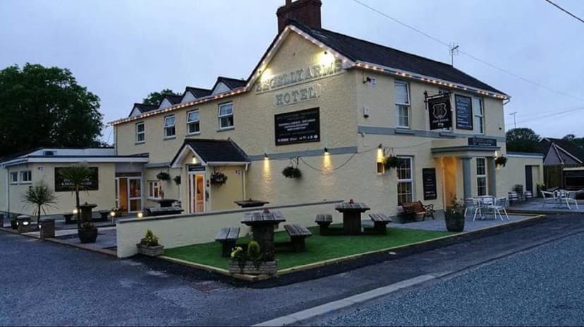 The Begelly Arms Hotel exterior with outdoor seating area illuminated at dusk.