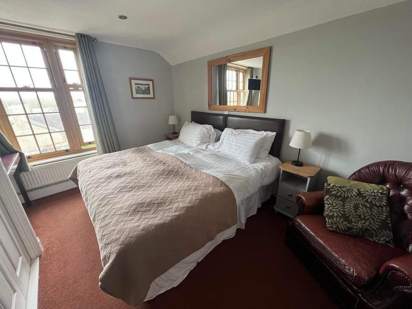 Bedroom in St. Govans Inn, Bosherston with double bed, leather armchair, and window view.