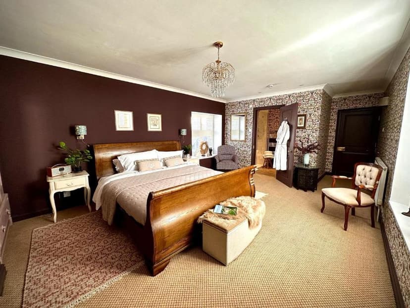 Bedroom with dark wood sleigh bed, crystal chandelier, and patterned wallpaper.