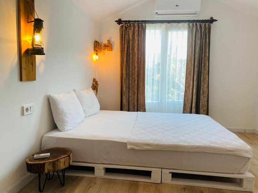 Minimalist bedroom with white bedding, wood pallet bed frame, and lantern wall light