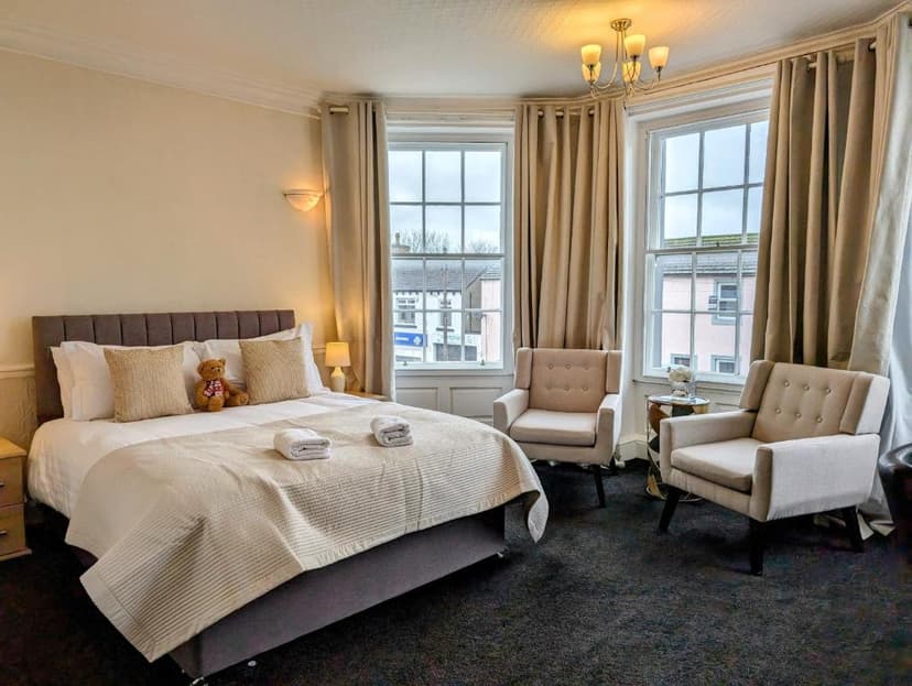 Bedroom in Graham Arms Inn with double bed, two armchairs, and bay windows.