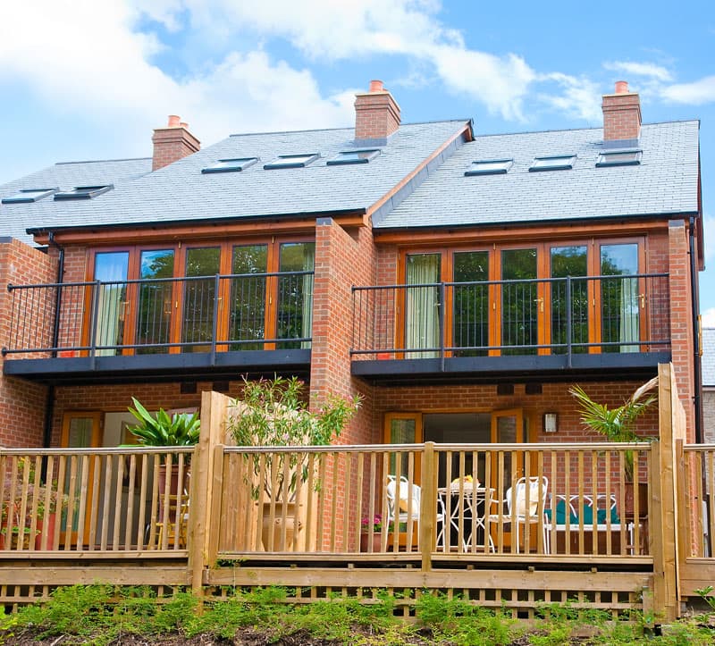 Brick holiday retreat with balconies and wooden deck under a blue sky
