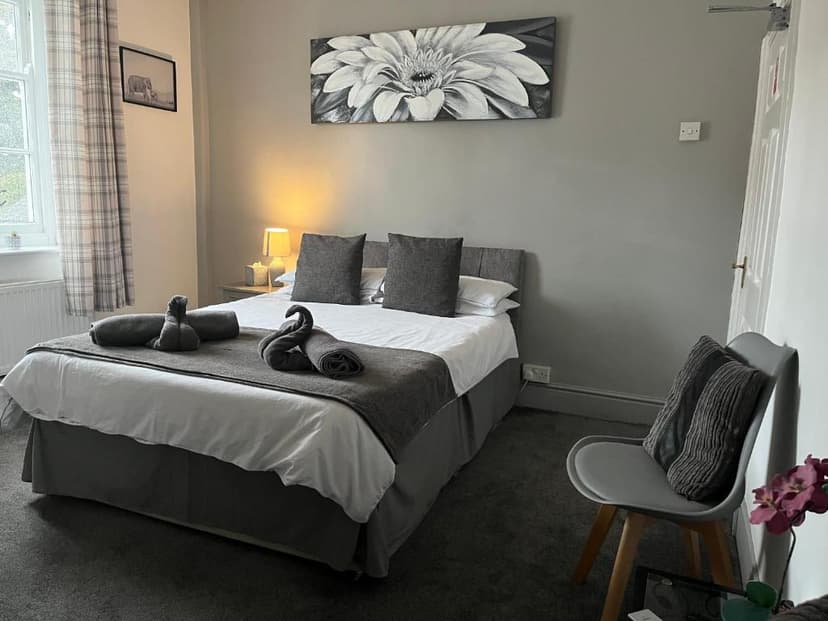Bedroom with double bed, grey decor, towel swans, and large floral artwork.