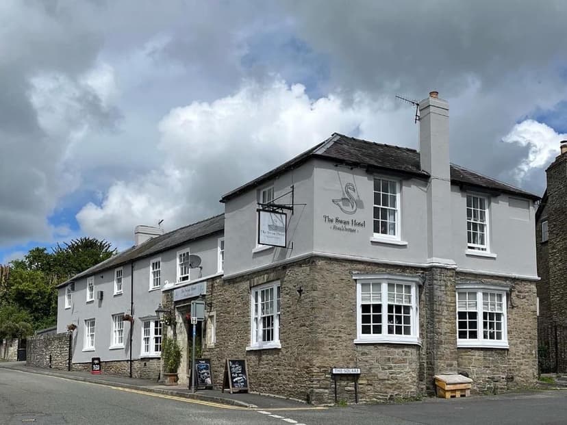 The Swan Hotel breakhouse with stone base and grey upper story on a street corner.