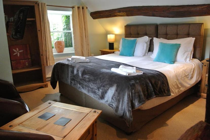 Bedroom in The Horse & Jockey Inn with large bed, wooden furniture, and window view.