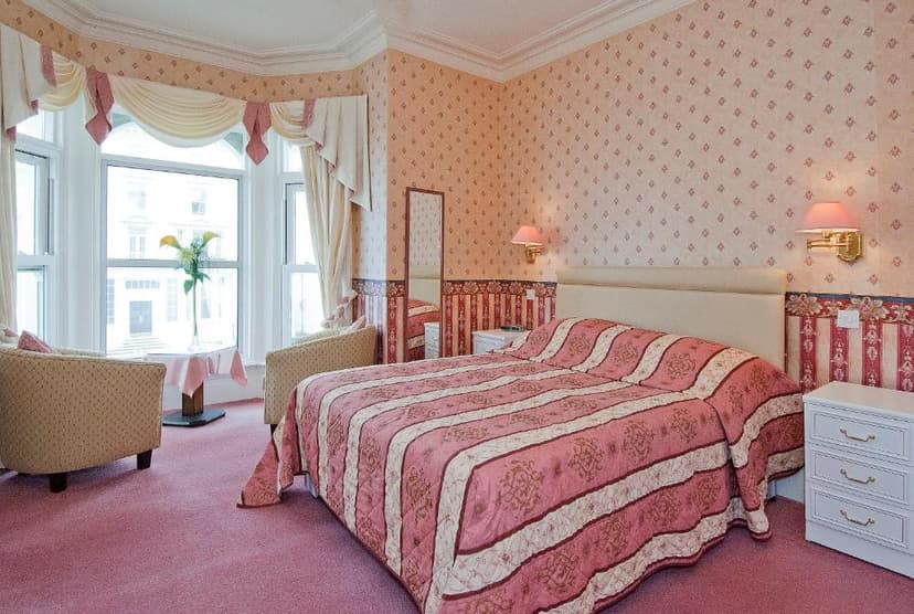 Bedroom in White Heather Hotel with pink patterned wallpaper and striped bedding