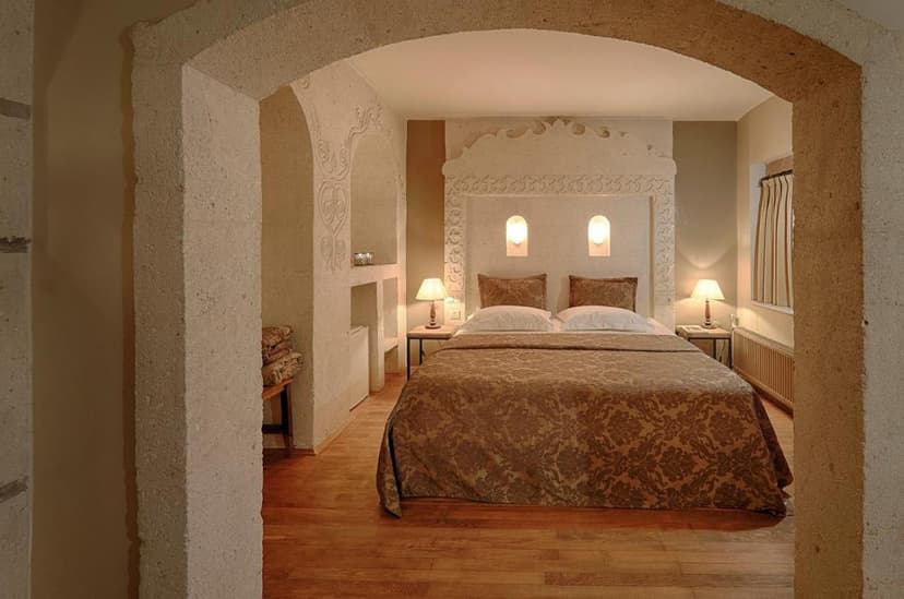 Hotel room with stone archway, carved headboard, and brown patterned bedding in Heybe Hotel & Spa.
