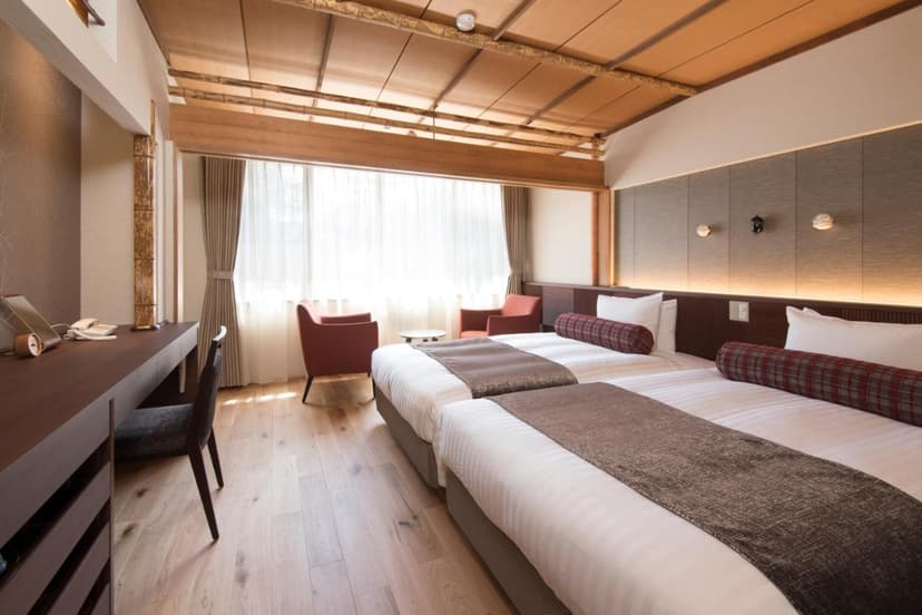 Twin beds in a modern hotel room at Hotel Shirakabaso in Kamikochi with wood accents.