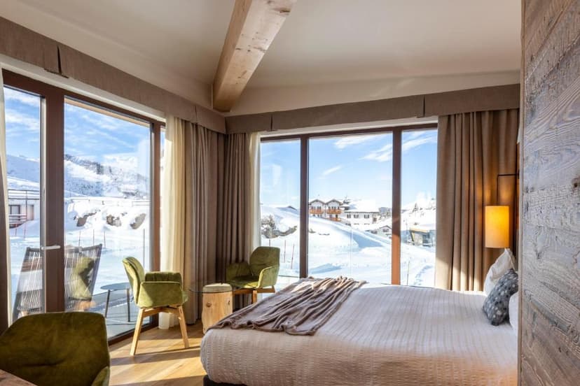 Hotel room with large windows overlooking a snowy alpine village and mountains in winter