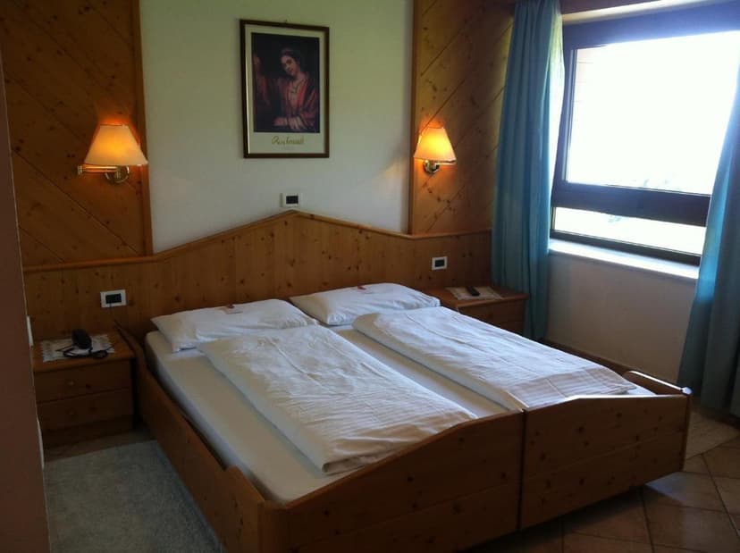 Wooden hotel room with twin beds, white bedding, and a window with blue curtains.