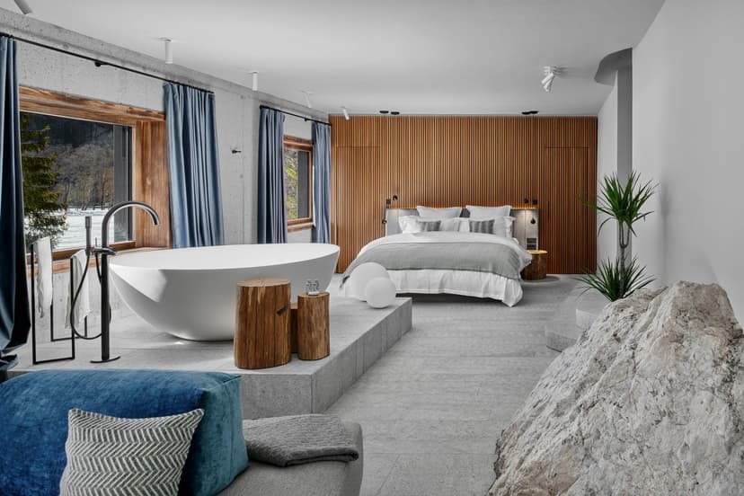 Boutique hotel suite with freestanding tub, wood accents, and view of snowy woods.