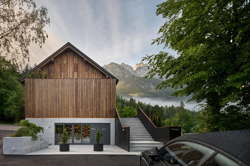 Boutique Hotel Milka entrance with wood facade, stone steps, and misty mountains backdrop.