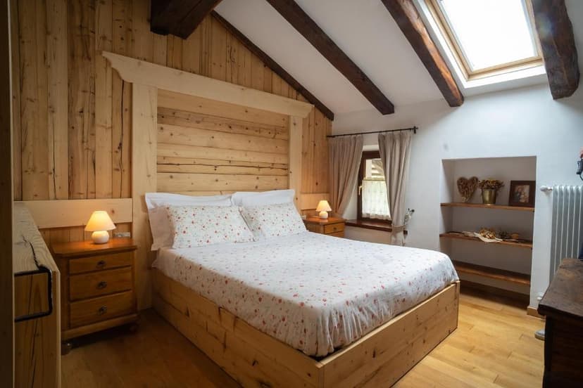 Bedroom with wooden walls, sloped ceiling, skylight, and floral patterned bedding.