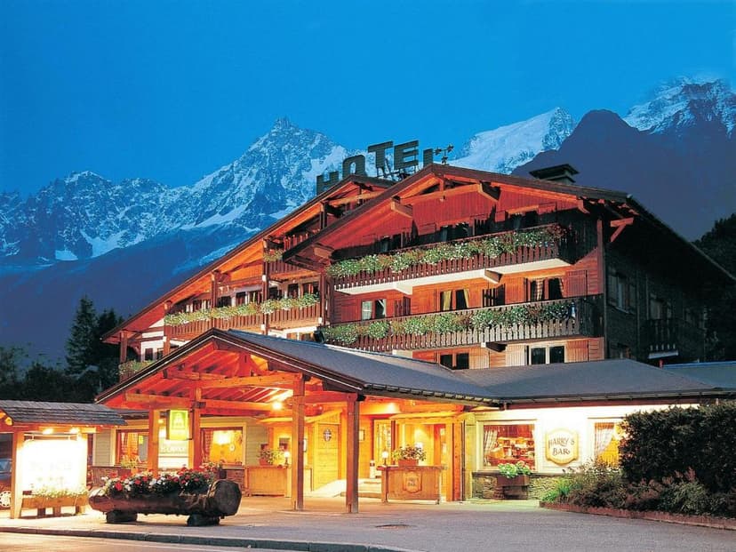 Chalet du Bois hotel entrance illuminated at dusk with snow-capped mountains in background