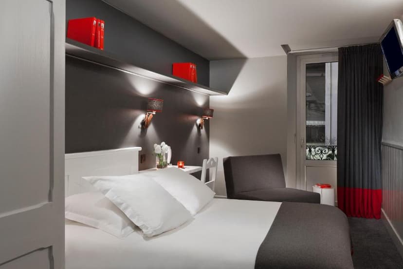 Modern hotel room with white bedding, dark gray accents, and red decor details.