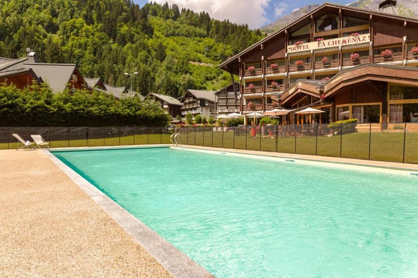 Outdoor swimming pool at Hotel La Chemenaz with lush green mountainside backdrop.